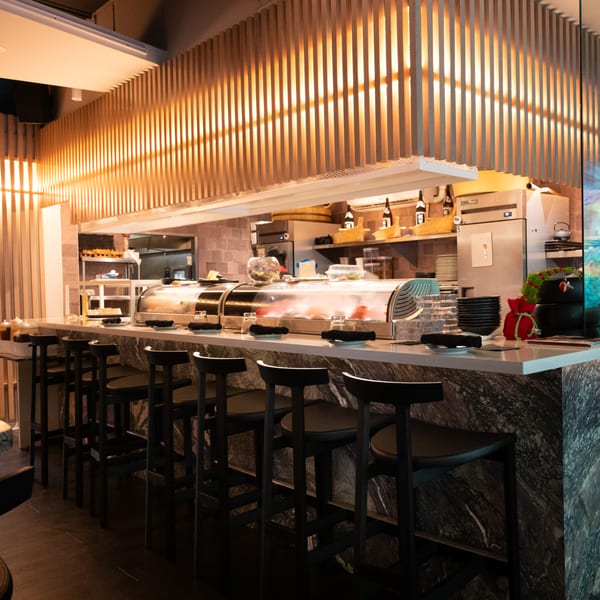 Lemongrass Asian Bistro sushi bar with a marble counter, bar stools, and sushi display cases.