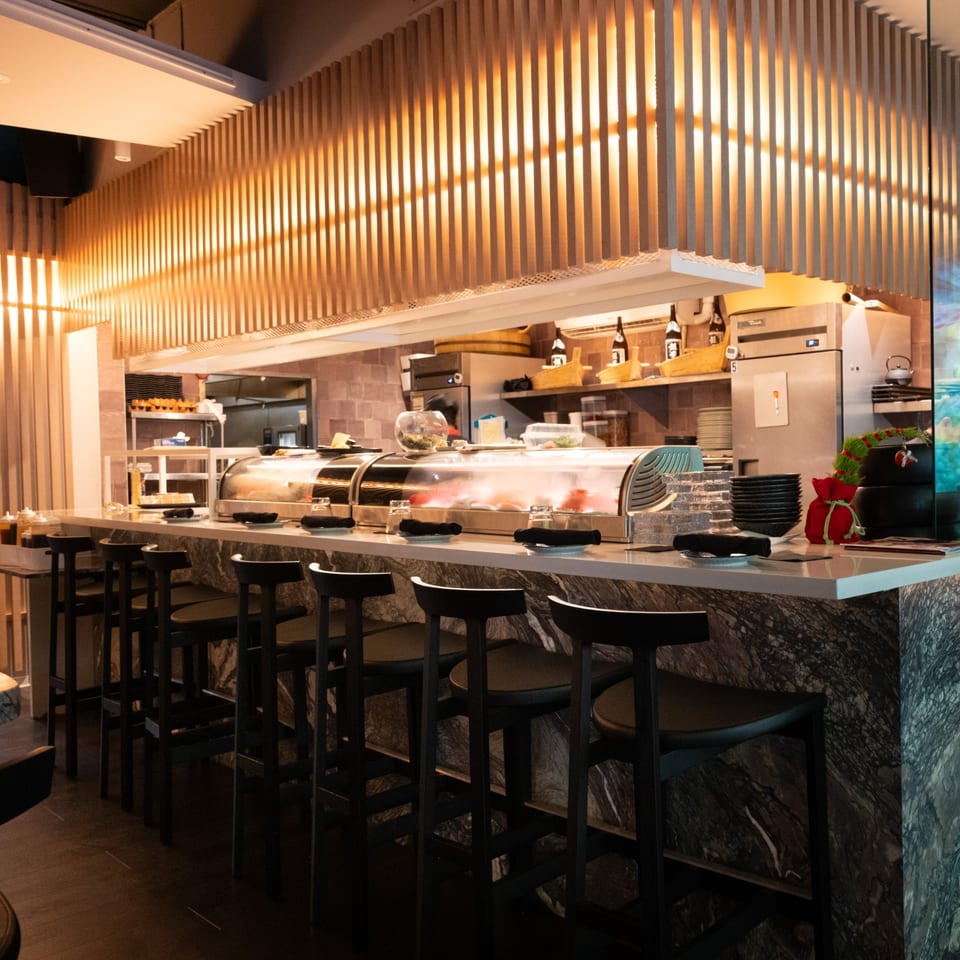 Lemongrass Asian Bistro sushi bar with a marble counter, bar stools, and sushi display cases.