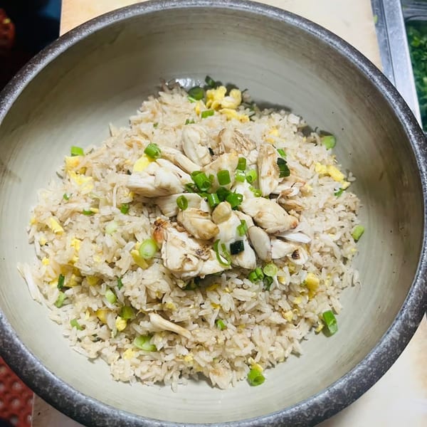 Lemongrass Asian Bistro's crab fried rice, topped with green onions and scrambled egg, in a ceramic bowl.