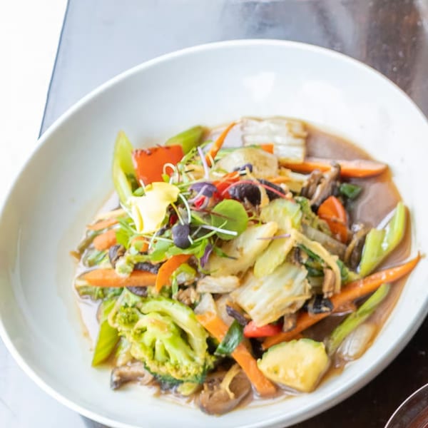 Lemongrass Asian Bistro's colorful stir-fried vegetables with broccoli, carrots, and mushrooms in a white bowl.