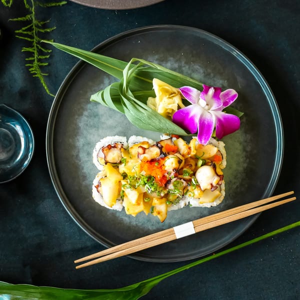 Lemongrass Asian Bistro sushi roll with octopus, scallops, roe, and green onions, garnished with an orchid.