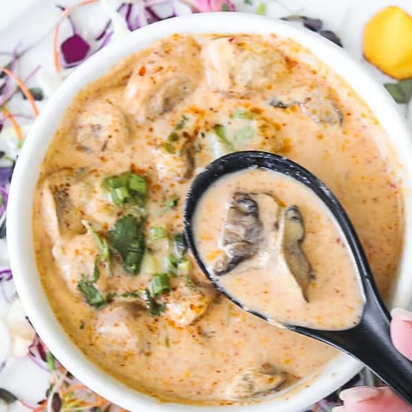 Creamy Lemongrass Asian Bistro soup with mushrooms and cilantro, served in a white bowl with a black spoon.