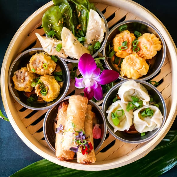 A bamboo steamer basket filled with various types of dim sum, including dumplings and spring rolls.