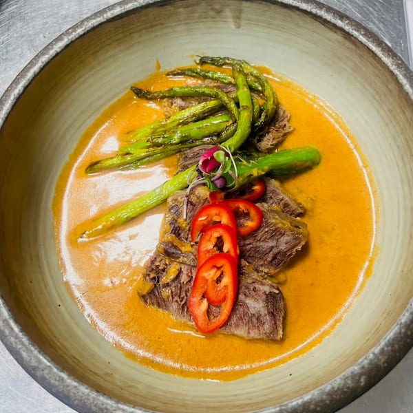 Lemongrass Asian Bistro's beef dish with asparagus, red peppers, and orange sauce in a bowl.