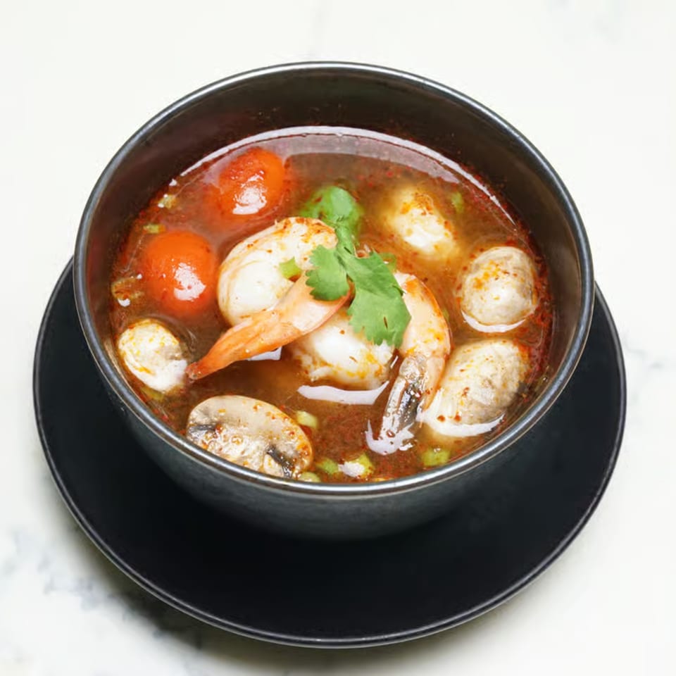 Lemongrass Asian Bistro's Tom Yum soup with shrimp, mushrooms, and tomatoes in a black bowl.